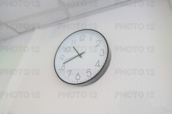 Plain white wall clock with black hands on the wall, Care Connect, vaccination kiosk for refugees, Calw, Germany