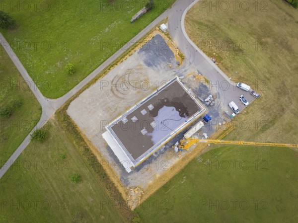 Aerial view of a construction site area with vehicles and a crane next to a partially completed building, green roof, house construction, climate neutral
