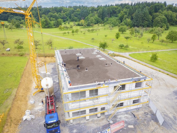 Construction site with a building under construction and a crane on a field, green roof, house construction, climate neutral