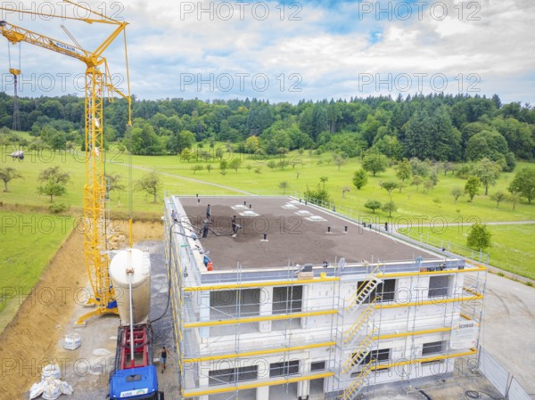A building under construction with a crane and surrounding landscape, green roof, house construction, climate neutral