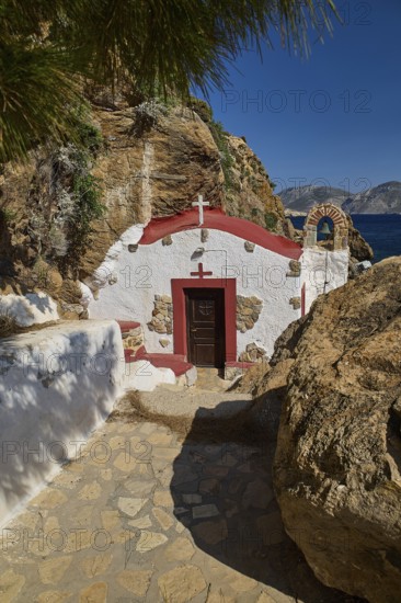 Legend, crab, shell fisherman, white chapel with red roof in rocky surroundings, paved path leading to the door, chapel, small church, Agia Kavouradena monastery, Xirokambos, Leros, Dodecanese, Greek Islands, Greece