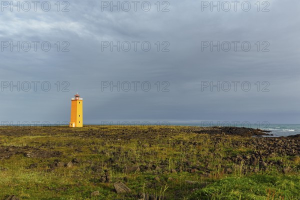 Orange lighthouse Selvogsviti in a meadow, Selvogur, south coast, Iceland