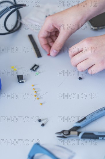 Hands working with small electronic components and tools on a table