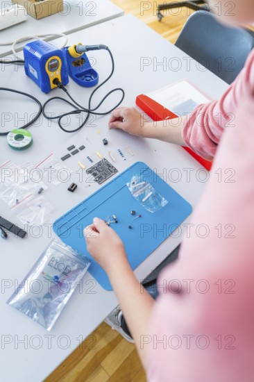 Person working on electronic components on a workbench with blue and red accents