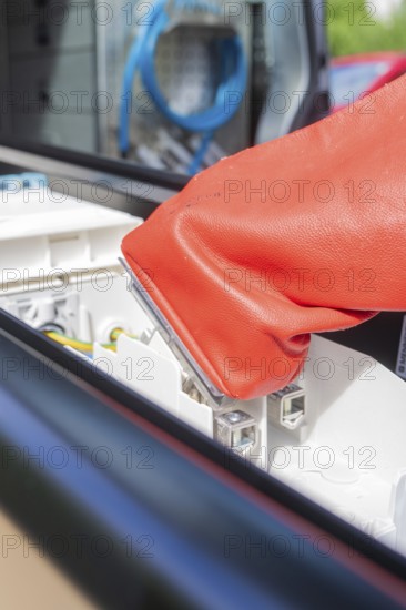 Red glove focusses on safe work with electrical connections, assembly of a charging station for electric cars, Calw, Germany