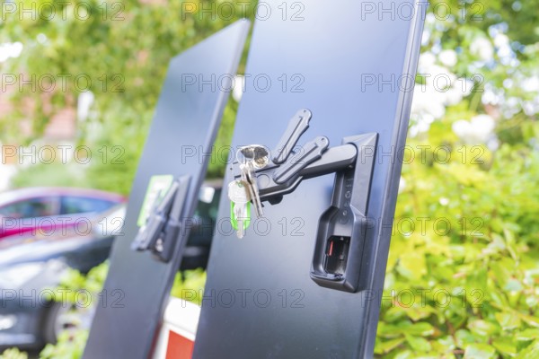 Black panels with a bunch of keys on a lock, installation of a charging station for electric cars, Calw, Germany