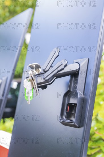 A bunch of keys hanging from a lock on a black background in a close-up, installation of a charging station for electric cars, Calw, Germany