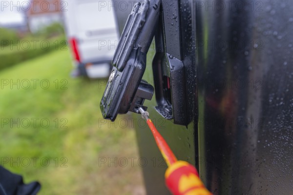 Screwdriver in use on a wet, black housing outdoors, assembly of a charging station for electric cars, Calw, Germany