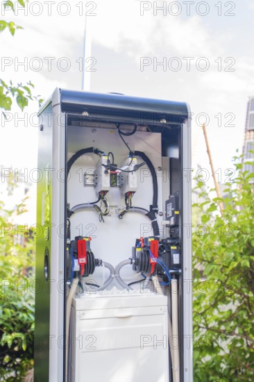 An open outdoor power box in front of a blue sky and green bushes, installation of a charging station for electric cars, Calw, Germany