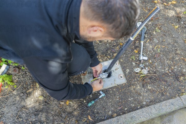 Man installs cables outdoors with tool support, assembly of a charging station for electric cars, Calw, Germany