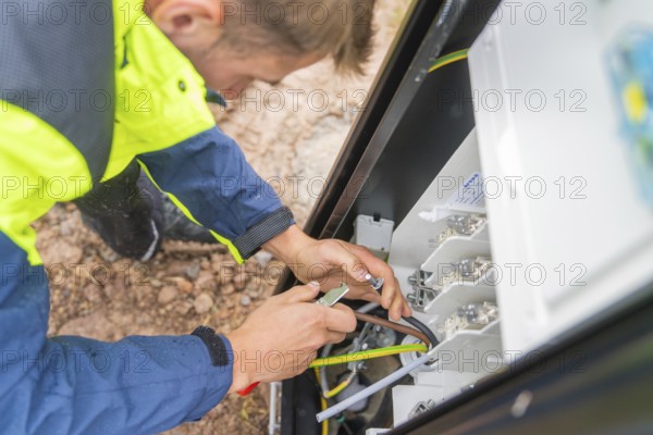 A person uses a tool to carry out work on an electrical switch box, assembly of a charging station for electric cars, Calw, Germany