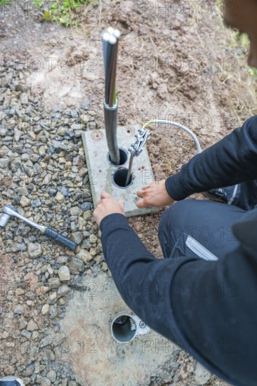 Worker attaching electrical cables to a grounding device on the ground, assembly of a charging station for electric cars, Calw, Germany