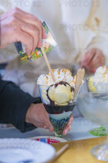 A delicious ice cream sundae with cream and waffle is held by a hand, chocolate sauce visible, Retro Freizeitpark Poppeltal Riesenrutschbahn, Enzklösterle, Black Forest, Germany