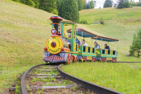 A colourful mini train runs on narrow tracks through a green landscape, children on board, Retro Freizeitpark Poppeltal Riesenrutschbahn, Enzklösterle, Black Forest, Germany