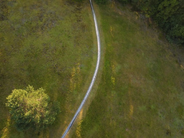 Winding path on a green meadow, in a peaceful sunlit atmosphere, Retro Freizeitpark Poppeltal Riesenrutschbahn, Enzklösterle, Black Forest, Germany