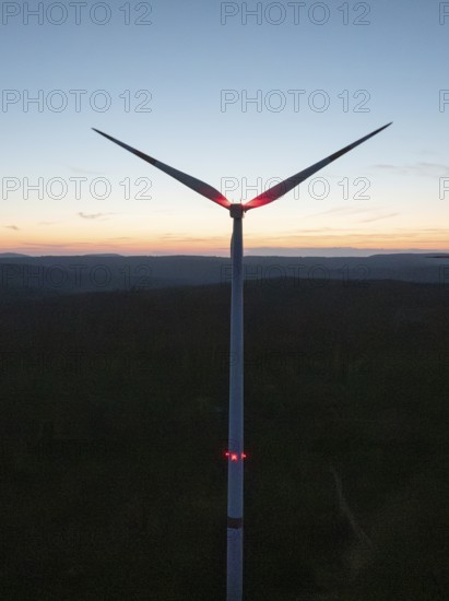 Wind turbine in front of a colourful sunset on the horizon. The sky glows in blue, red and orange, Simmersfeld, Black Forest, Germany
