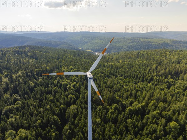 A single wind turbine in front of a vast wooded landscape under a bright sky, Simmersfeld, Black Forest, Germany