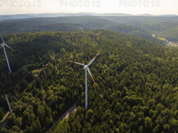A wind turbine in the middle of a vast green forest under a blue sky in daylight, Simmersfeld, Black Forest, Germany