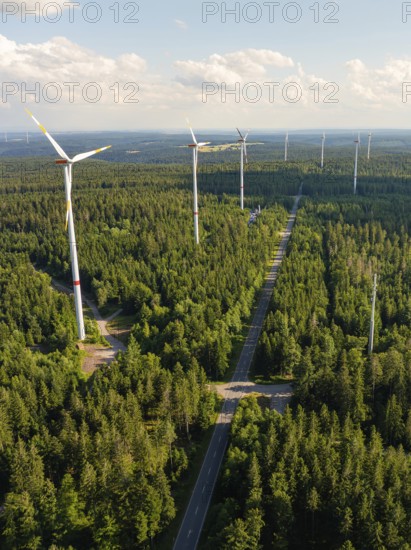 Row of wind turbines along a road through a dense forest in daylight, Simmersfeld, Black Forest, Germany