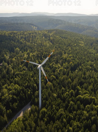 Single wind turbine surrounded by dense forest and green hills under a clear sky, Simmersfeld, Black Forest, Germany