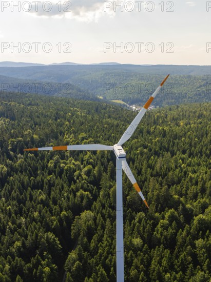 Close-up of a wind turbine in front of a vast wooded landscape under a blue sky, Simmersfeld, Black Forest, Germany