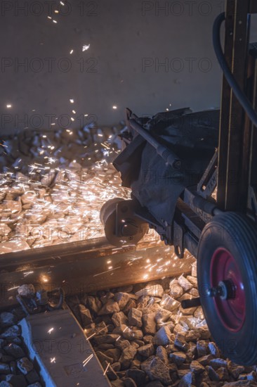 Close-up of sparks during track work, machine in operation on ballast, grinding work on the Hermann Hesse railway, Ostelsheim, district of Calw, Germany