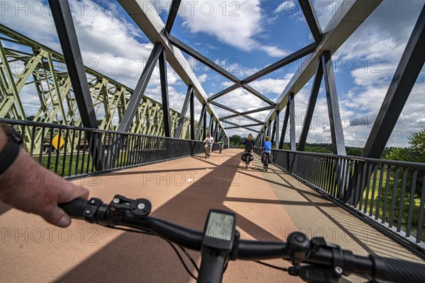 Ride over the De Massover cycle path bridge, over the Meuse south of Nijmegen, near Cuijk, part of the MaasWaalpad long-distance cycle path, 12 km between Nijmegen and Cuijk, built in 2021, for 15 million euros, Meuse river crossing for cyclists and pedestrians, part of a cycle path network, used by many commuters, next to a railway bridge, Netherlands