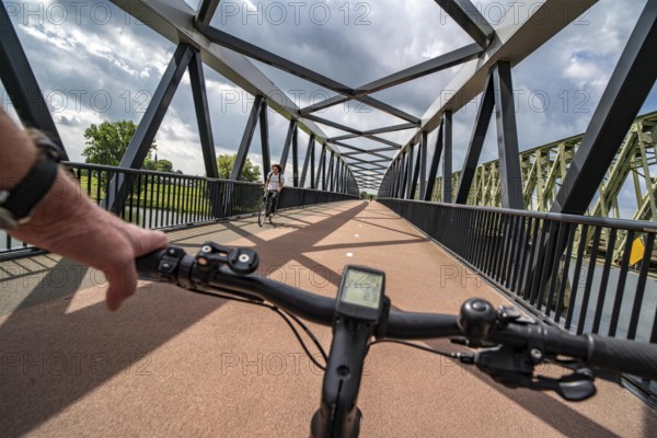 Ride over the De Massover cycle path bridge, over the Meuse south of Nijmegen, near Cuijk, part of the MaasWaalpad long-distance cycle path, 12 km between Nijmegen and Cuijk, built in 2021, for 15 million euros, Meuse river crossing for cyclists and pedestrians, part of a cycle path network, used by many commuters, next to a railway bridge, Netherlands