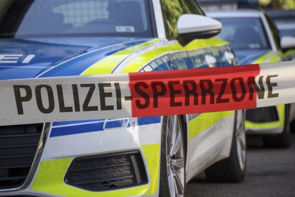 (Photomontage) Symbolic image of a police operation: police cordon in front of emergency vehicles