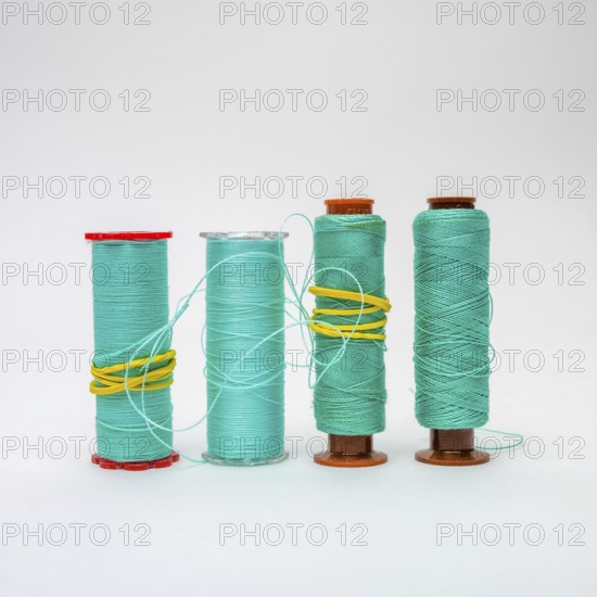 A collection of turquoise bobbins of thread is displayed, showcasing different sizes and textures