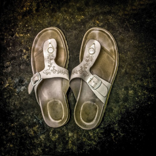 Worn sandals resting on a textured surface showcasing rustic charm and everyday wear in a casual setting