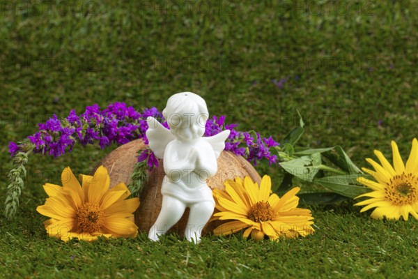 White angel figure with purple and yellow flowers on a green lawn