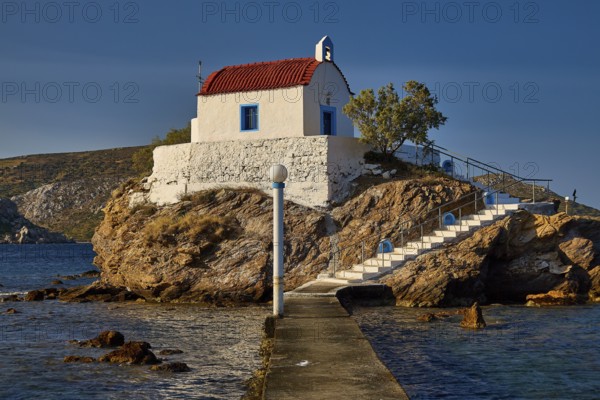 A small church with a red roof lies on a rock, accessible via steps and a pier, chapel, church, Agios Isidoros, rocky islet, Bay of Gourna, Kokkali, Leros, Dodecanese, Greek Islands, Greece