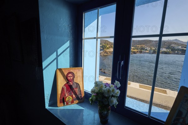 Icon on a windowsill overlooking the sea, surrounded by blue light and a bouquet of flowers, chapel, church, Agios Isidoros, rocky islet, Gourna Bay, Kokkali, Leros, Dodecanese, Greek Islands, Greece
