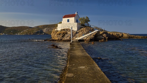A pier leads to a church perched on a rock, surrounded by the calm sea, chapel, church, Agios Isidoros, rocky islet, Gourna Bay, Kokkali, Leros, Dodecanese, Greek Islands, Greece