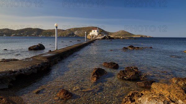 A stone pier leads to a church standing on a rock in the calm sea, chapel, church, Agios Isidoros, rocky islet, Gourna Bay, Kokkali, Leros, Dodecanese, Greek Islands, Greece