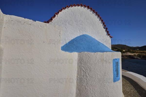 Close-up of a white church wall with blue accents and red roof, chapel, church, Agios Isidoros, rocky islet, Gourna Bay, Kokkali, Leros, Dodecanese, Greek Islands, Greece