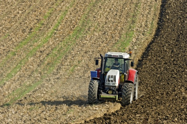 Harvested grain field being turned into a field by Steyr tractor with plough, Hohenpolding, Erding, Upper Bavaria, Bavaria, Germany
