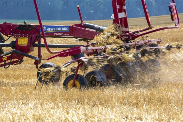 Hastings, Michigan - A farmer uses a New Holland ProTed 3625 tedder to aerate her crop. A tedder spreads out hay or straw to allow quicker drying before baling