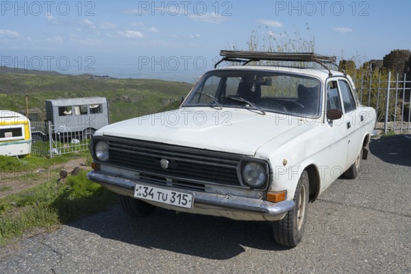 An old car is standing on a rural road with mountains and clear sky in the background, vintage car, Volga GAZ 24-10, Aragazotn province, Armenia