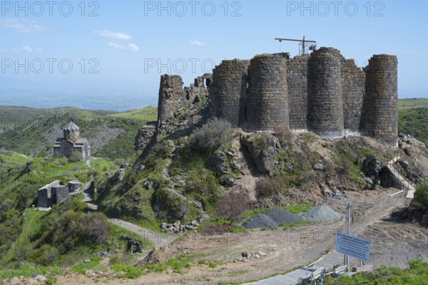 A historic fortress ruin rises above a green landscape under a blue sky, Amberd Fortress and Mother of God Church, Vahramashen Church, Vahramashen Surp Astvatsatsin, Amberd Church, Aragazotn Province, Armenia