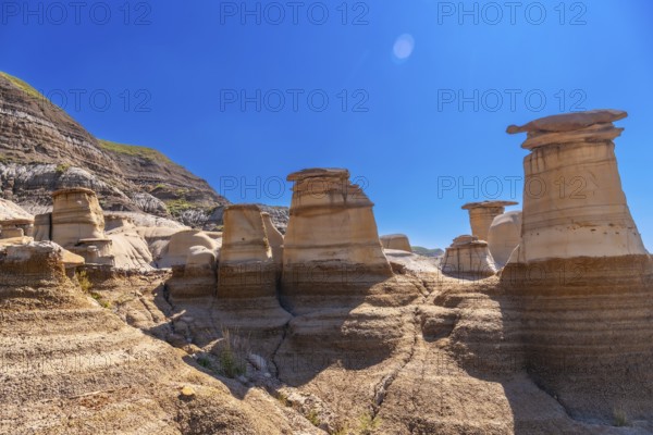 Breathtaking view of the otherworldly hoodoo rock formations in drumheller, alberta, canada, showcasing the unique geological features of the canadian badlands under a vibrant blue sky