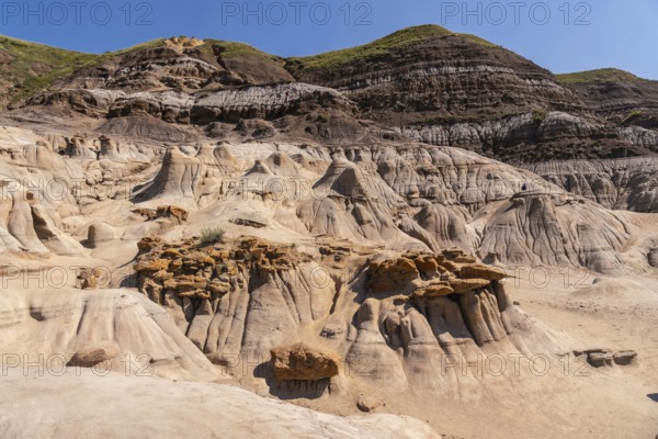 Sunlight illuminates the otherworldly landscape of the drumheller hoodoos, showcasing unique geological formations rising from the arid terrain under a vibrant blue sky in the canadian badlands