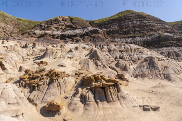 Breathtaking panoramic view of the arid drumheller valley showcasing unique hoodoo formations under a clear blue sky, highlighting the geological wonders of the canadian badlands