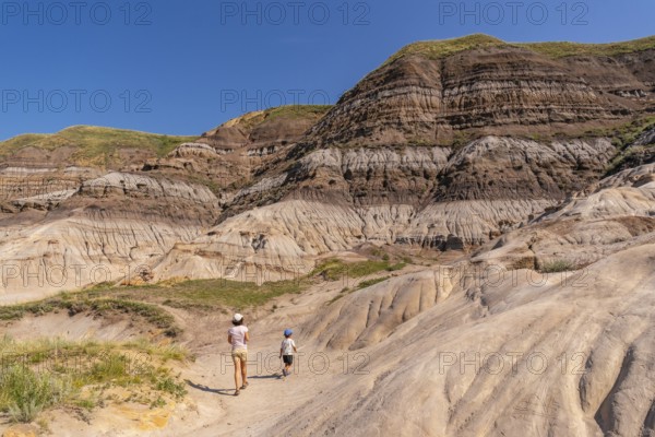 Tourists walking through horseshoe canyon under the bright summer sun, discovering the stunning geological formations and unique landscapes of drumheller, alberta, canada