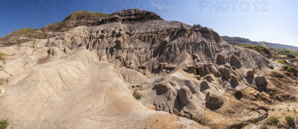 Panoramic view of unique hoodoo rock formations in drumheller, alberta, showcasing the geological wonders of the canadian badlands under a clear blue sky