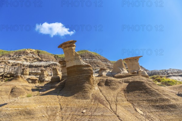 Breathtaking hoodoo rock formations dominate the arid landscape of drumheller, canada, under a vibrant blue sky, creating a dramatic and otherworldly scene