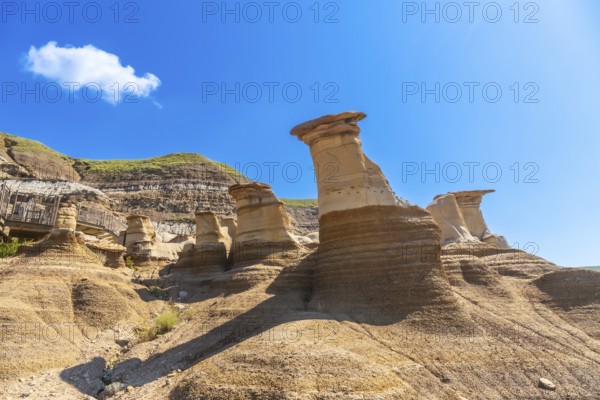 Breathtaking sandstone hoodoos rise majestically in drumheller valley, showcasing unique geological formations under a vibrant blue sky, creating a stunning landscape in the canadian badlands
