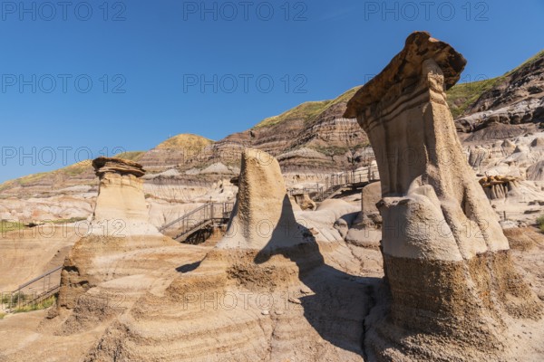 Breathtaking view of unique sandstone formations, known as hoodoos, dominating the landscape of drumheller valley in the canadian badlands under a vibrant blue sky