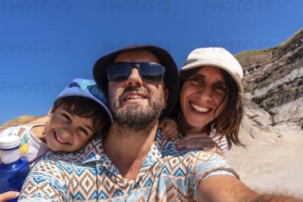 Happy family with a small child taking a selfie portrait with the arid landscape of drumheller, alberta, canada, in the background on a sunny summer day